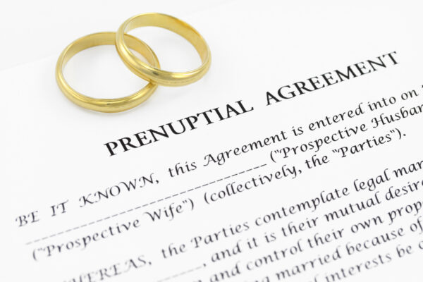 Two wedding bands on top of a blank prenuptial contract.