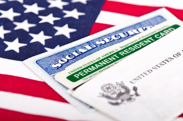 A Social Security card and a Permanent Resident Card resting on top of a United States flag.